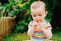 Baby putting in his mouth a flower of a garden, concept of dangers for babies