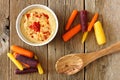 Baby rainbow carrots with hummus, overhead view on rustic wood Royalty Free Stock Photo