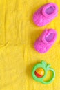 Baby rattle and booties on yellow background Royalty Free Stock Photo