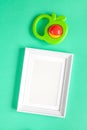 Baby rattle and photo frame on green background Royalty Free Stock Photo