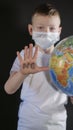 Baby reaches forward hand STOP, NO. Boy is holding a globe, a model of the planet Earth. Boy is careful of the virus