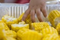 Baby reaching hand to to shiny yellow sweet corn