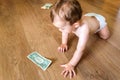 Baby reaching some dollar bills, wasted family savings concept Royalty Free Stock Photo