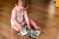 Baby reaching some dollar bills, wasted family savings concept Royalty Free Stock Photo