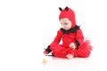 Baby with a red demon disguise watching a pacifier
