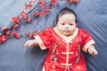 Baby in red dress on blue cloth with flower and looking. Concept Chinese New Year.