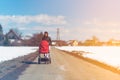Baby in red stroller in fields countryside with mother. Relax in nature in Winter sunny day Royalty Free Stock Photo