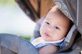 Baby Relaxing in a Stroller Outside. Toddler Boy with slight smile rests, looking out with curious eyes, enjoying the comfort and Royalty Free Stock Photo