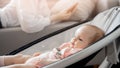 Baby rests in automatic bed for sleeping, while mother works via Internet phone or communication in social networks Royalty Free Stock Photo