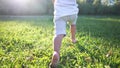 baby running in the park with bare feet. close-up of the kid leg runs in the summer on the green grass at sunset in the Royalty Free Stock Photo