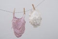 BabyÃ¢â¬â¢s beach clothes drying on a clothesline. Tiny white Panama hat and pink bikini on white background.