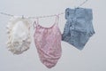 BabyÃ¢â¬â¢s beach clothes drying on a clothesline. Tiny white Panama hat, pink bikini and striped shorts on white background.