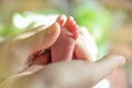 Baby s feet closeup picture. Mother s hands holding child s foot. Little girl s fingers at front