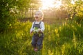 Baby`s first independent steps in the garden in sunlight. Cute summer blond girl laughing in the garden. Royalty Free Stock Photo