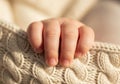 A baby\'s hand gently grasps a soft, cream-colored knitted blanket. Royalty Free Stock Photo