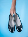 Baby`s hand holds stylish leather shoes on blue background. Royalty Free Stock Photo