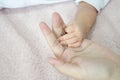 Baby`s hand on mother`s palm over soft fur background Royalty Free Stock Photo