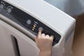 The baby`s hand pressing the power button on the air purifier to clean up the polluted air Royalty Free Stock Photo