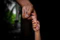 A baby`s hands holding tightly A senior man`s old age finger. Family, Generation, Support and people concept.