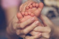 Baby`s legs and mom`s hands are interlaced