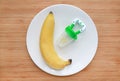 Baby`s nibbler and banana on white plate against wooden background. Organic baby food concept Royalty Free Stock Photo