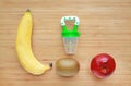 Baby`s nibbler and fresh ripe fruits apple, banana and kiwi on wood background. Organic baby food concept Royalty Free Stock Photo