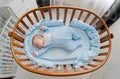 Baby`s restful sleep. Newborn baby in a wooden crib. The baby sleeps in the bedside cradle. Royalty Free Stock Photo