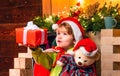 Baby Santa boy holding and looking at Christmas box gift trying to guess what is inside it. Little kid at Santa`s hat Royalty Free Stock Photo