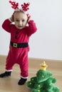 Baby in Santa`s dress with deers horns