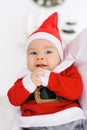 Baby in a Santa suit lies or sits in dad`s arms and smiles in anticipation of Christmas Royalty Free Stock Photo
