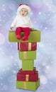 Baby seated on a stack of christmas presents Royalty Free Stock Photo