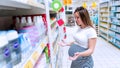 Baby shampoo pregnancy woman buy. Young pregnant woman shopping on baby bath shampoo bottle on supermarket background Royalty Free Stock Photo