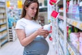 Baby shampoo pregnancy woman buy. Young pregnant woman shopping on baby bath shampoo bottle on supermarket background Royalty Free Stock Photo