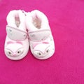 Baby shoes kept beautifully in pink background with bow band