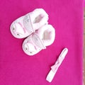 Baby shoes kept beautifully in pink background with bow band