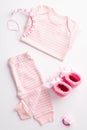 Baby shower concept. Top view vertical photo of pink shirt pants knitted shoes dummy and teether chain on isolated white Royalty Free Stock Photo