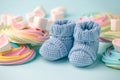 Baby shower decoration - it is a girl. Rainbow sweetness and knitted blue booties socks on blue background. First birthday,