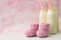 Baby shower decorative table with copy space, pink baby girl booties and bottles with milk in pastel background, idea of baby show