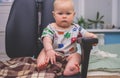 The baby sits in a computer chair with a serious look like a boss
