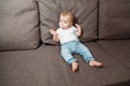 Baby sits on couch with a baby`s dummy in his mouth Royalty Free Stock Photo