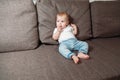 Baby sits on couch with a baby`s dummy in his mouth Royalty Free Stock Photo