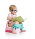 Baby sitting on chamberpot with book Royalty Free Stock Photo