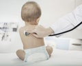 Baby sitting in the doctors office with the doctors hand checking heart beat with a stethoscope Royalty Free Stock Photo