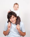 Baby sitting on father neck on white