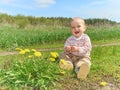 Baby sitting on a green meadow with yellow flowers dandelions Royalty Free Stock Photo