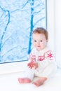 Baby sitting at window watching snow covered trees Royalty Free Stock Photo