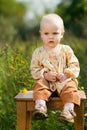 Baby sitting on wooden chair in field. nature walks with kids.