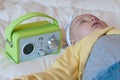 A baby with onesie sleeps in the bed