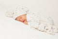 Baby sleeping with Blanket. Newborn lying on Stomach in White Bed. Cute Baby Face Portrait in Knitted Hat. One Month Child Bedtime