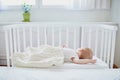 Baby sleeping in co-sleeper crib attached to parents ` bed
